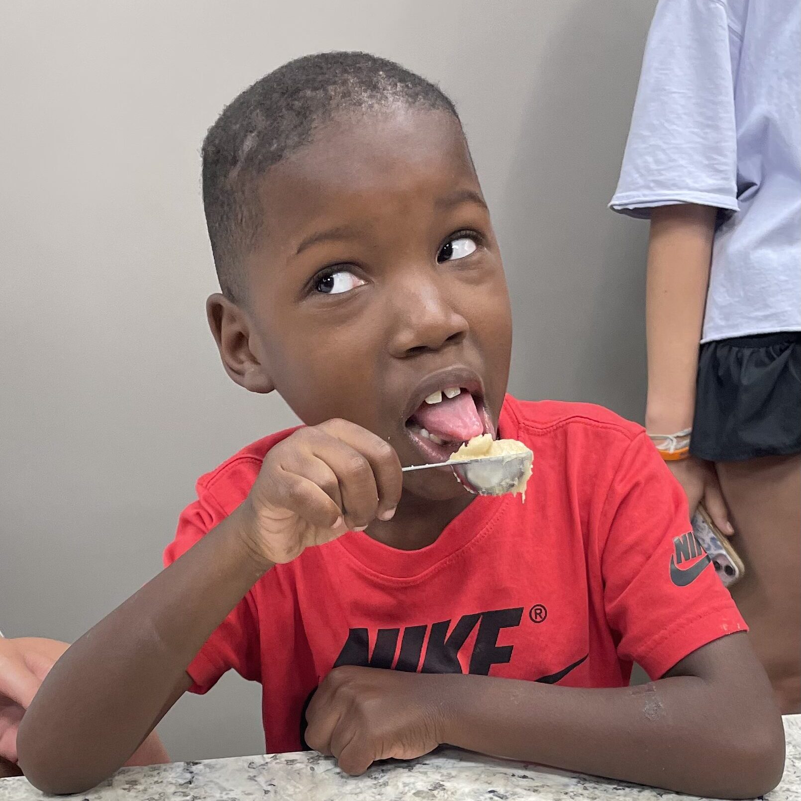 Camper taste-testing in teaching kitchen at Camp Kamassa.